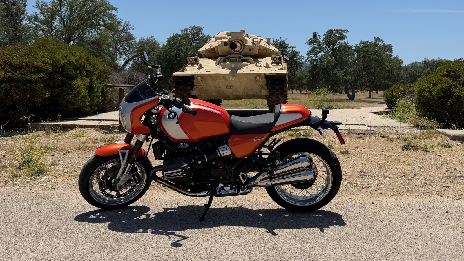 2025 BMW R 12 S with Lava Orange solo seat cowl parked in front of vintage armored tank